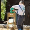 Deček uporablja eko leseni mlin za pesek za igro na prostem