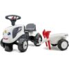Bel otroški traktor z rdečo prikolico na beli podlagi.
