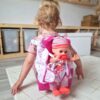Deklica se igra z dojenčkom v vozičku – otroška igrača