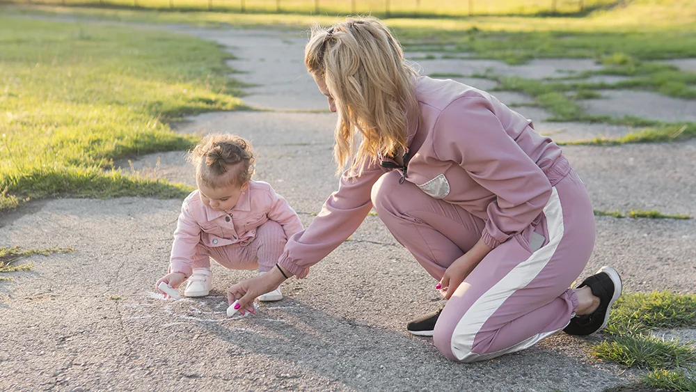 Mama in otrok rišeta s kredo na pločnik